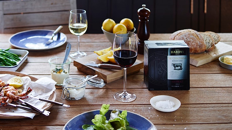 A box of wine sits among a beautifully styled dinner table laden with food
