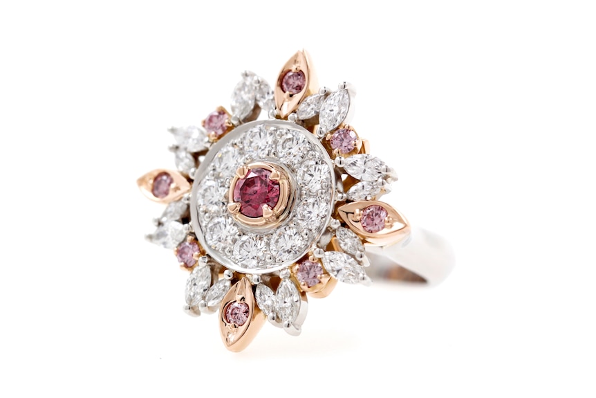 A large ring with diamond-like and pink jewels shaped like the sun.