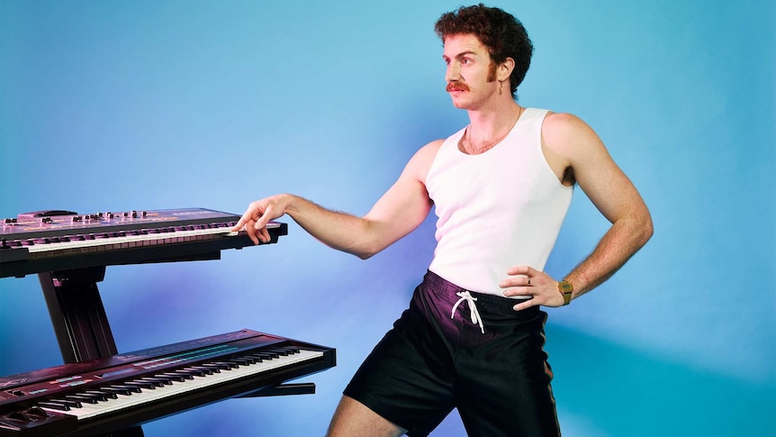A 2021 press shot of Tom Cardy playing keyboard against a blue backdrop