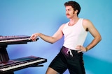A 2021 press shot of Tom Cardy playing keyboard against a blue backdrop
