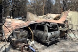 A burnt out car beneath a collapsed, smouldering shed in Cooroibah