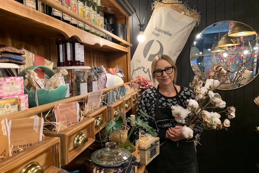 Female with glasses on holds a cotton bunch in her florist
