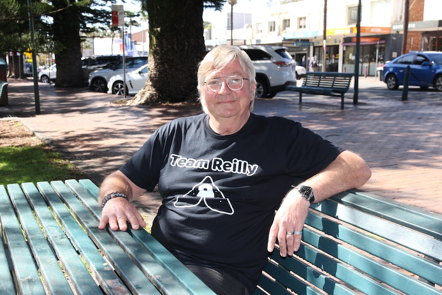 A man sits on a bench seat in the main street of Kiama