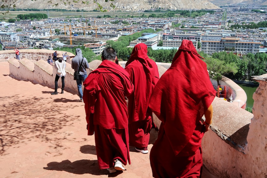 Tibetan Buddhist monks walk wearing red robes.