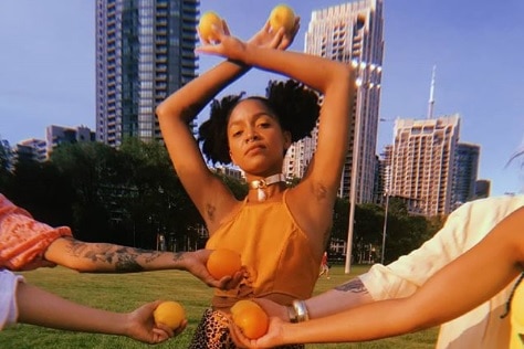 Janette King stands in a park with her arms in the air