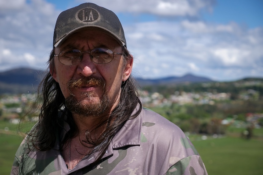 A man, wearing a hat, stands on a hill near Lithgow.