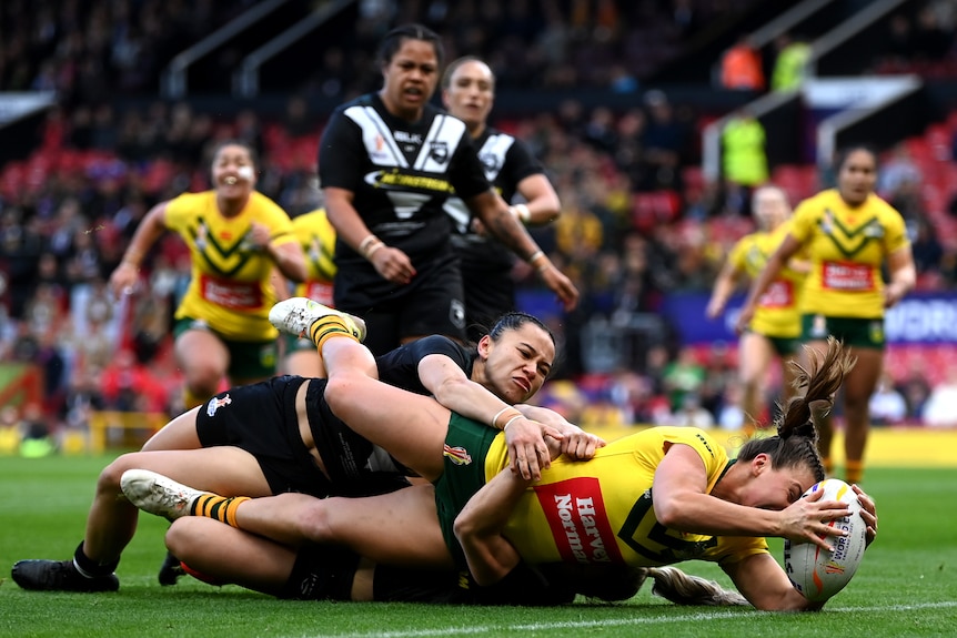 Jessica Sergis holds a rugby ball in front of her as she is tackled to the ground