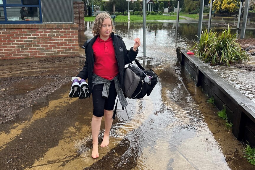 A boy wading through water outside school 