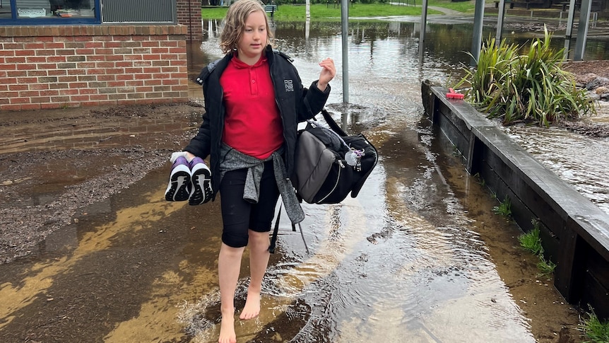 A boy wading through water outside school.