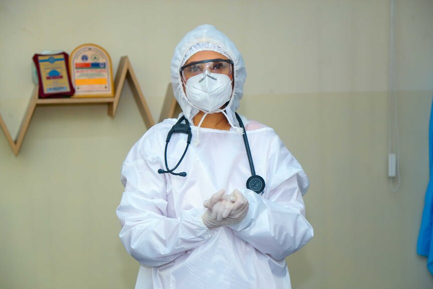 A woman in full PPE standing in an office
