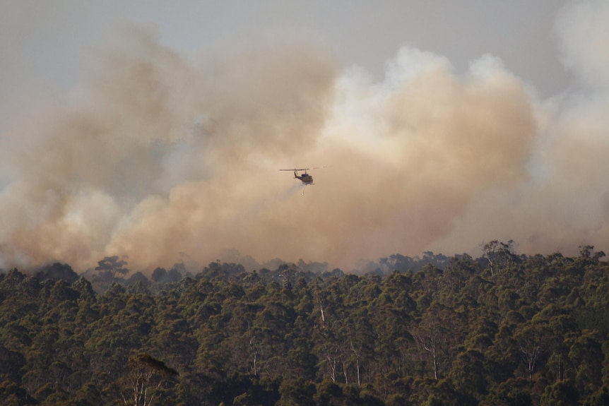 Bushfire smoke with a helicopter in the distance