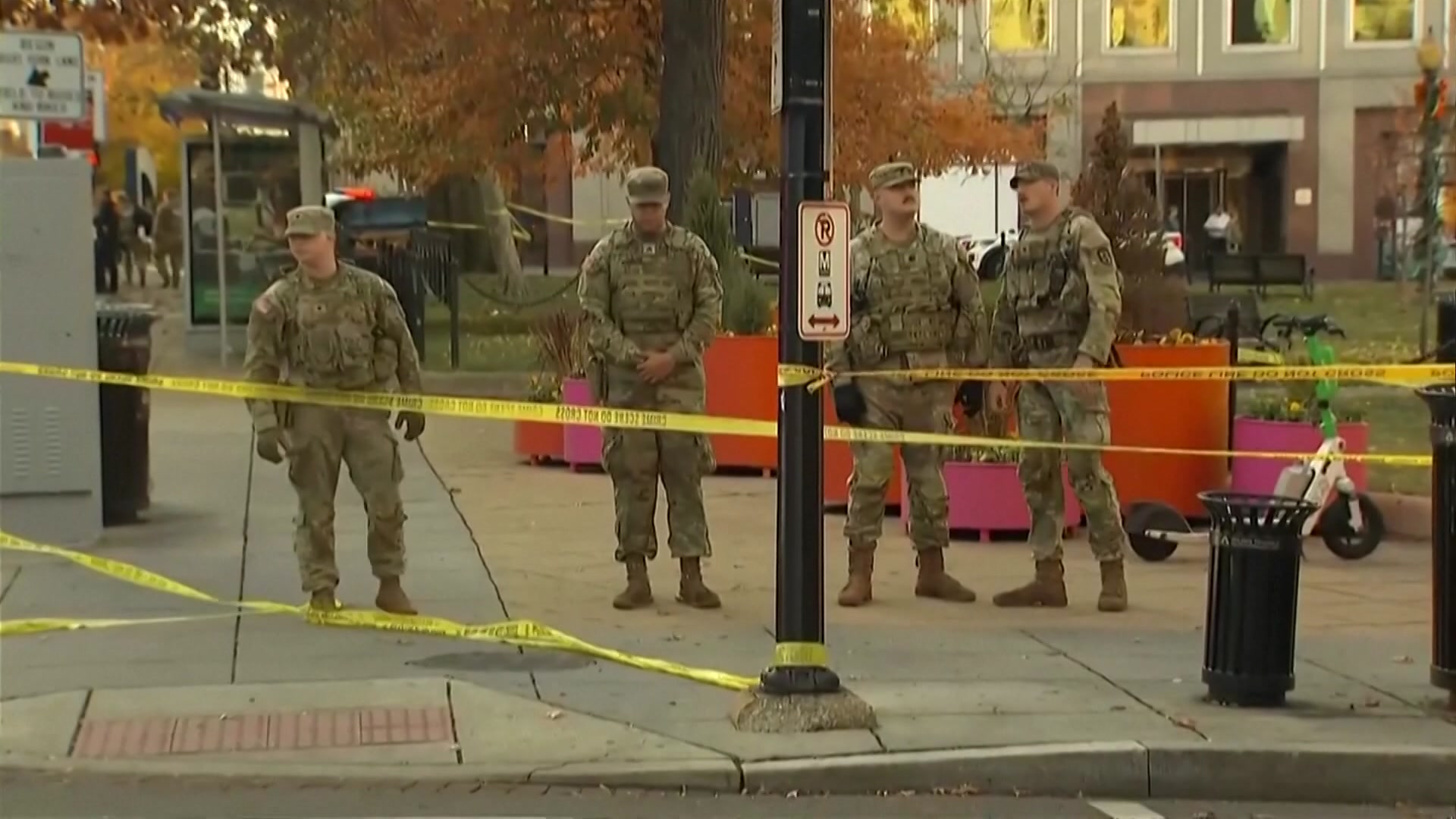 Four soldiers in military fatigues stand behind crime scene tape