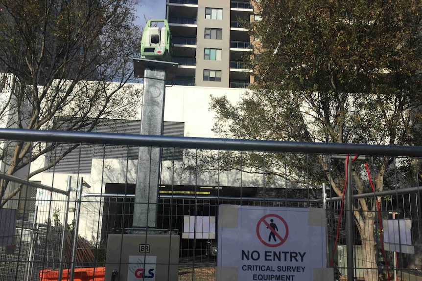 A fence with a no-entry sign in front of a high-rise building.