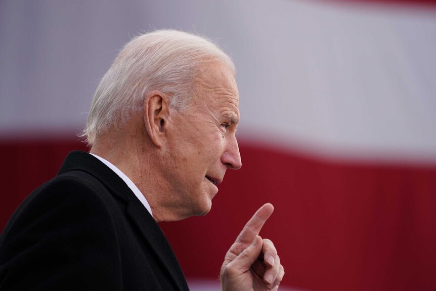 Joe Biden pointing with a US flag in the background