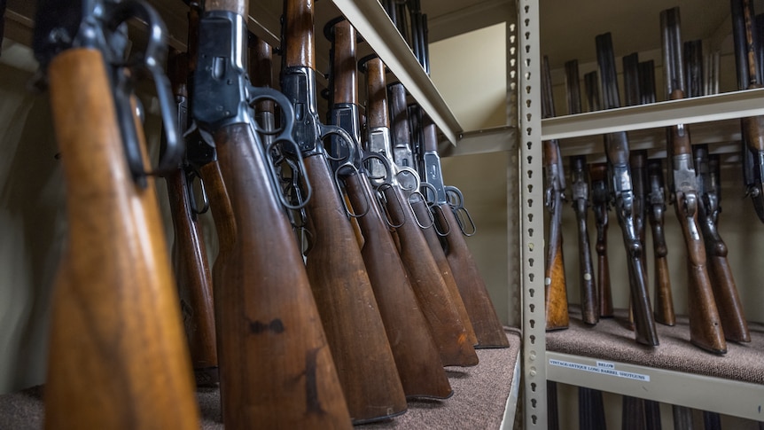 Prop guns are seen lined up in a row on a wall during an interview with a props expert.