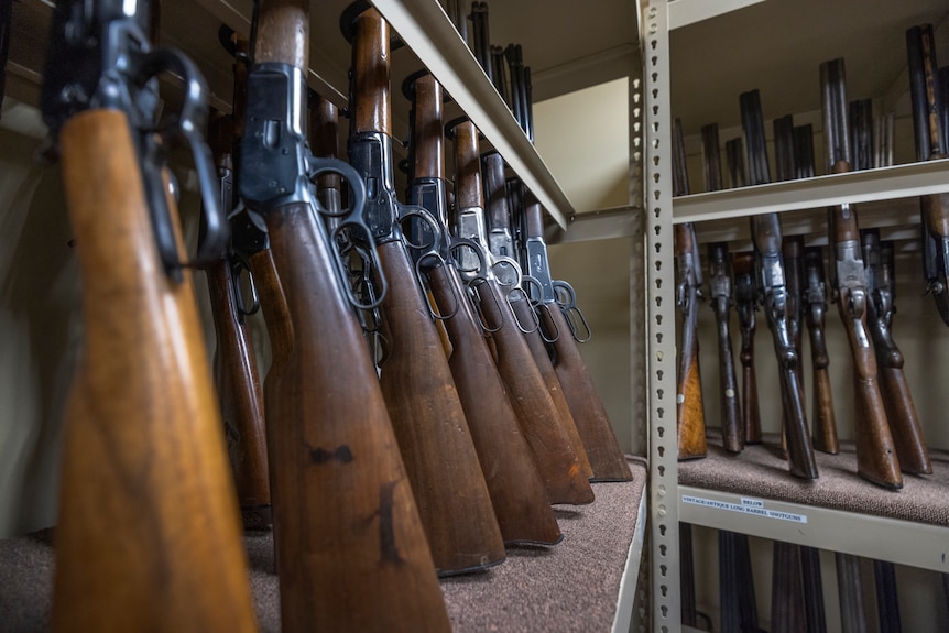 Prop guns are seen lined up in a row on a wall during an interview with a props expert.