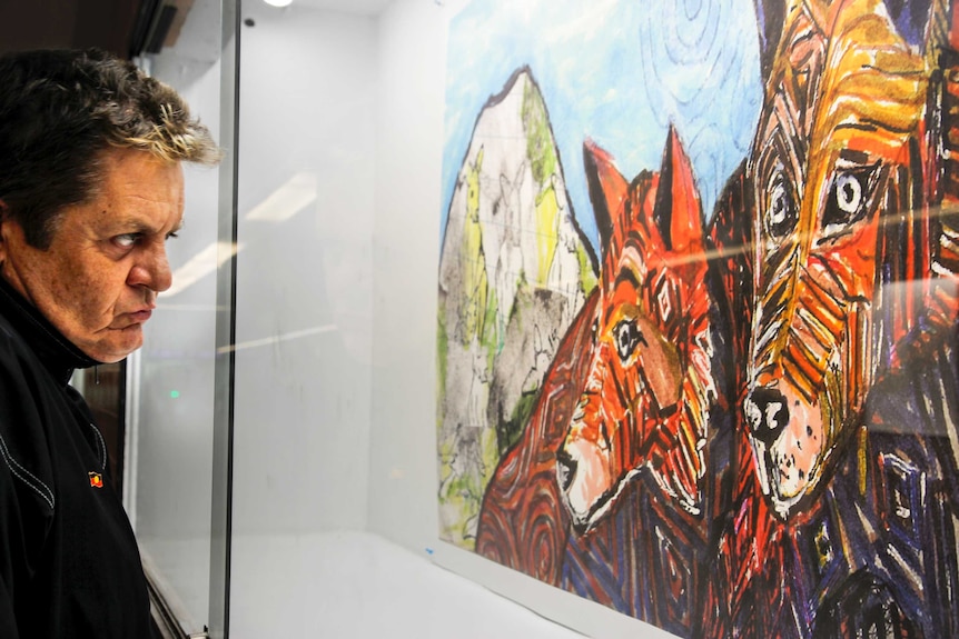 Peter Waples-Crowe looks at one of his mixed media pieces in his Dirty Dingo series.