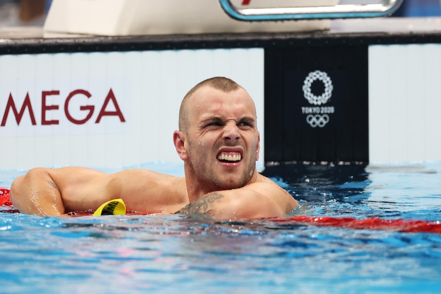 An Australian male swimmer leans over the ropes after his heat at the Tokyo Olympics.