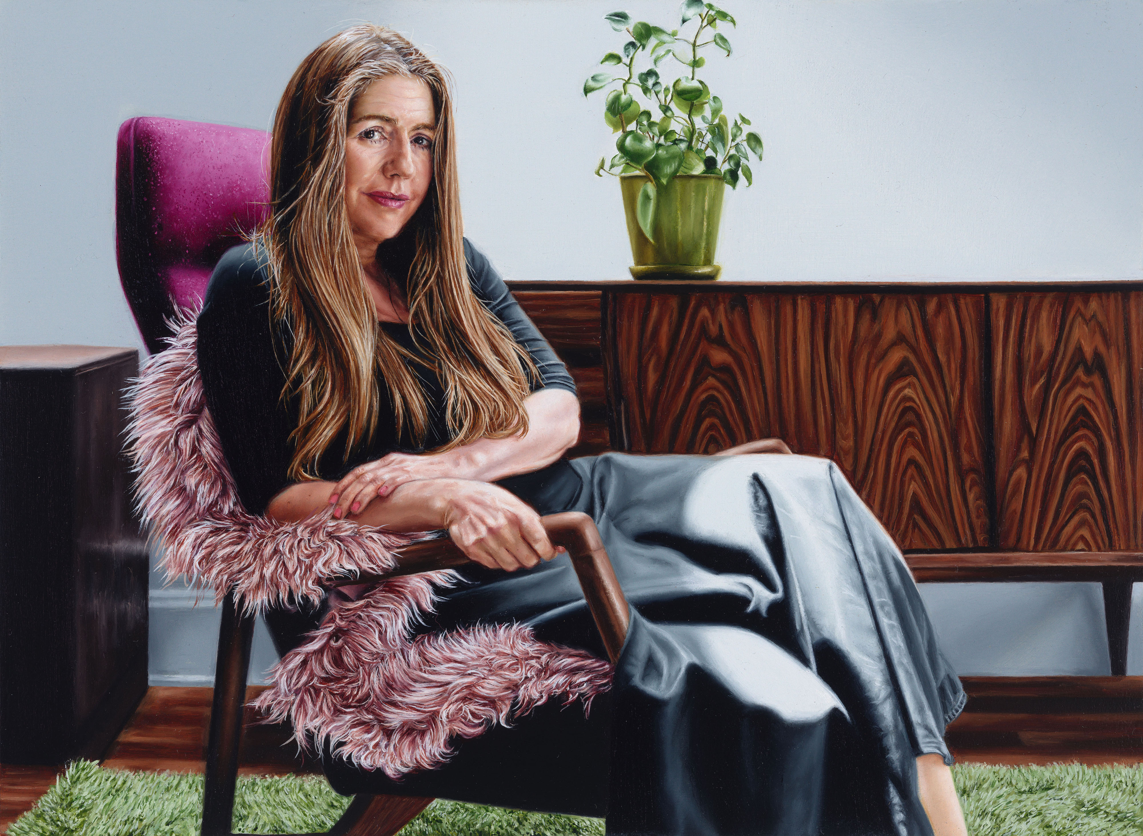 Portrait of Australian artist Patricia Piccinini sitting in a chair, with pot plant and credenza behind her