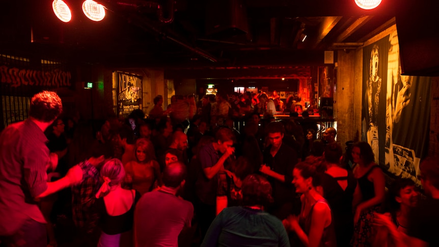 People dance inside a dimly lit bar.