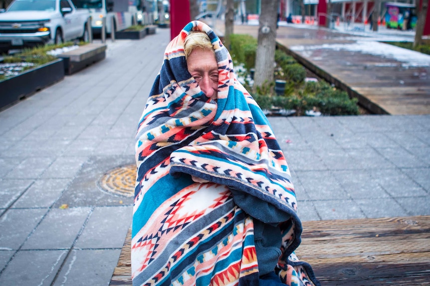 A woman with a multi-coloured blanket draped over her head