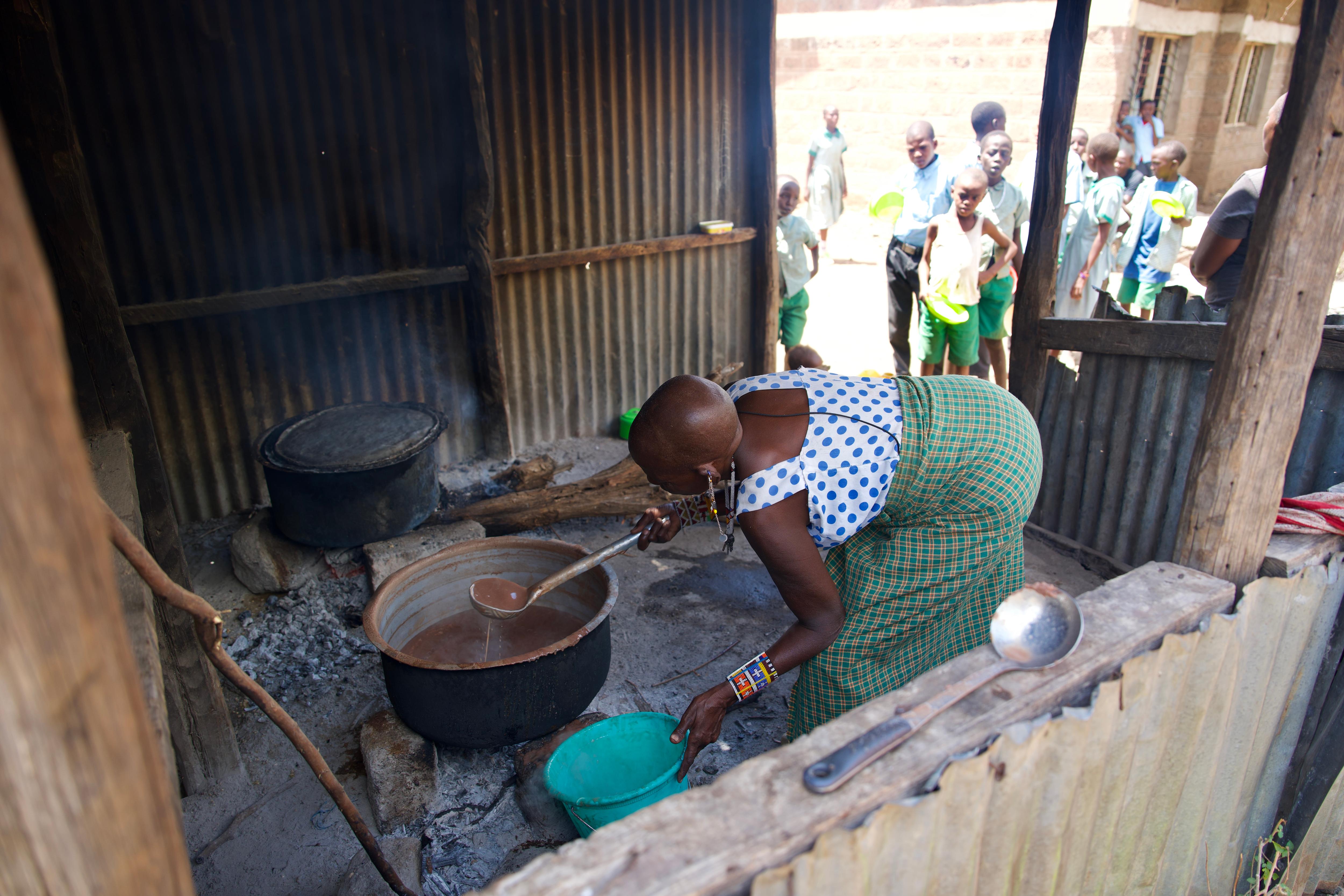 A woman pours soup for children in Kenya