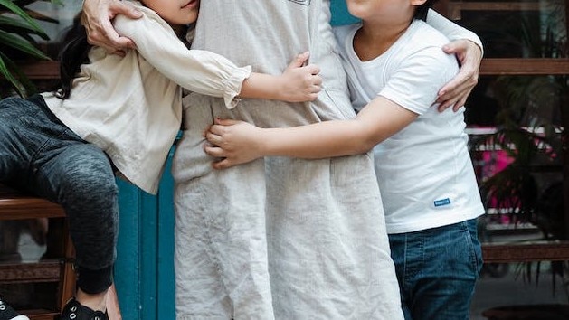 close crop of two children hugging their mum's waist