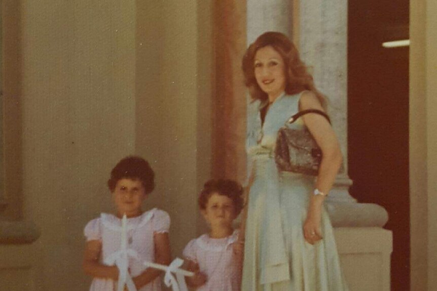 A woman standing with two children