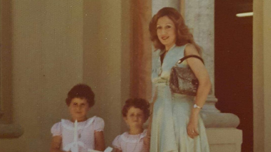 A woman standing with two children