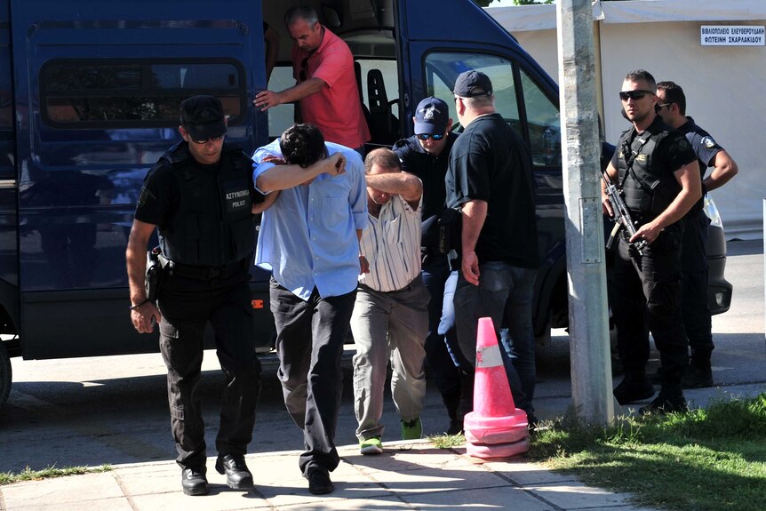 Turkish officers arrive escorted by police officers in Alexandroupoli, northern Greece.