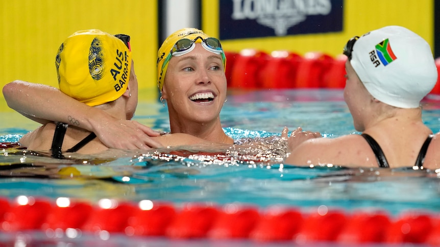 Emma McKeon hugs fellow Australian swimmer Holly Barratt in the Commonwealth Games pool.