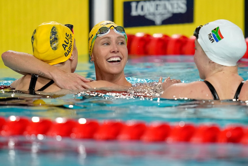 Emma McKeon hugs fellow Australian swimmer Holly Barratt in the Commonwealth Games pool.