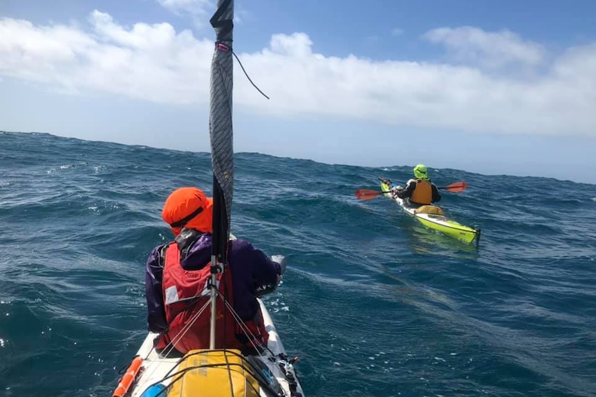 Two men in kayaks brave an ocean swell