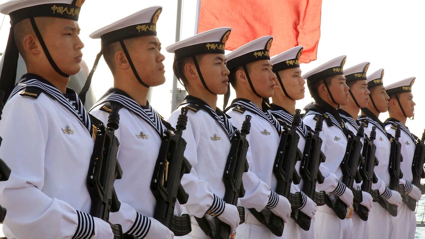 Chinese sailors stand at attention on the helipad of the Chinese frigate Yancheng.