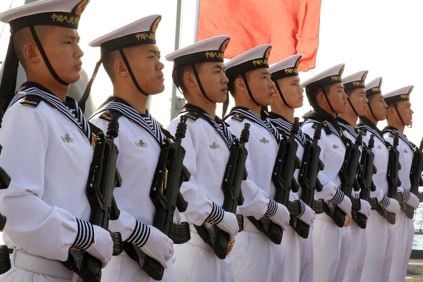 Chinese sailors stand at attention on the helipad of the Chinese frigate Yancheng.