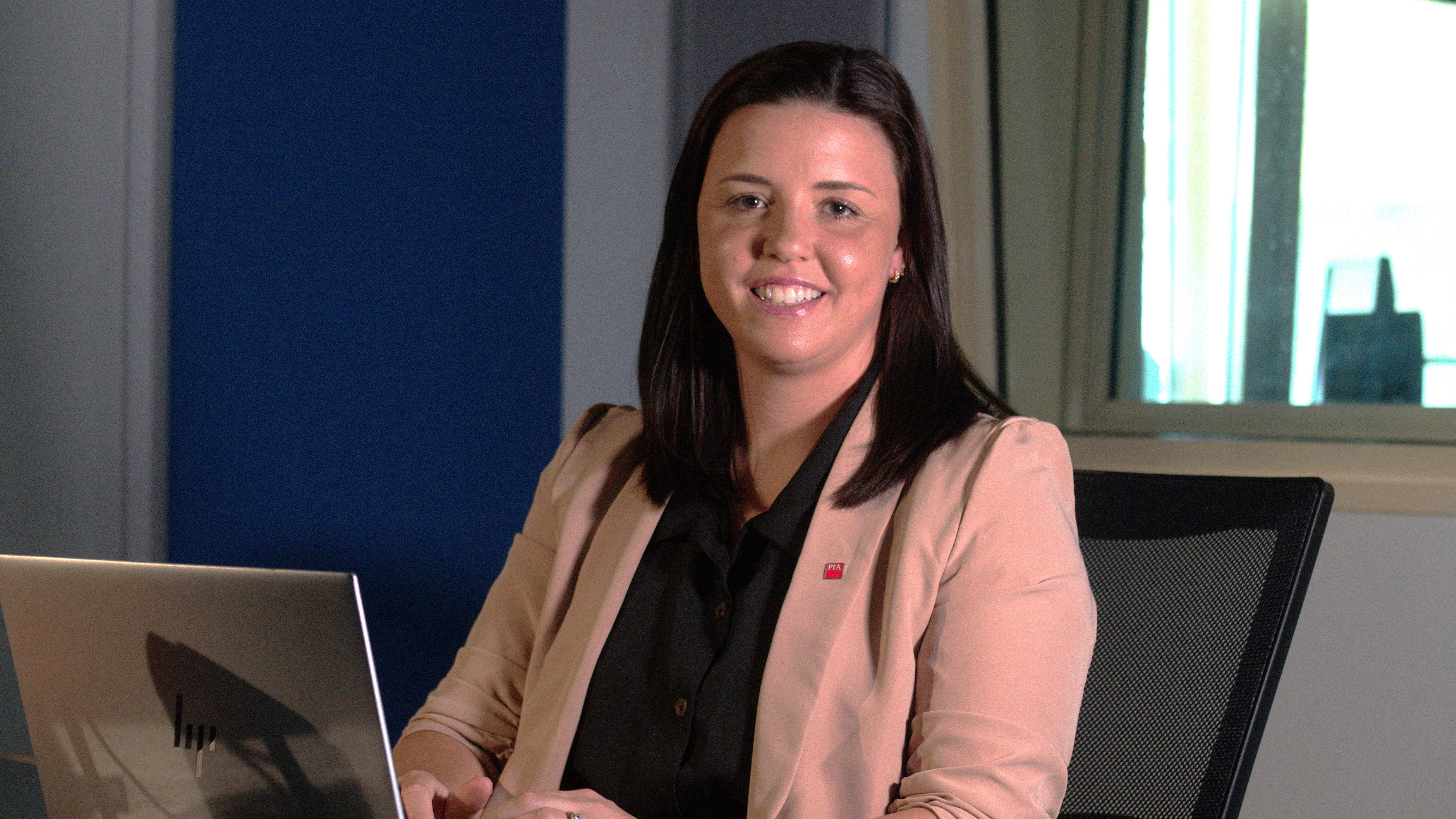 A woman working on a computer smiling at the camera. 