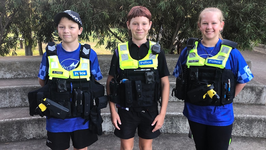 Three young school students dressed up in police gear.