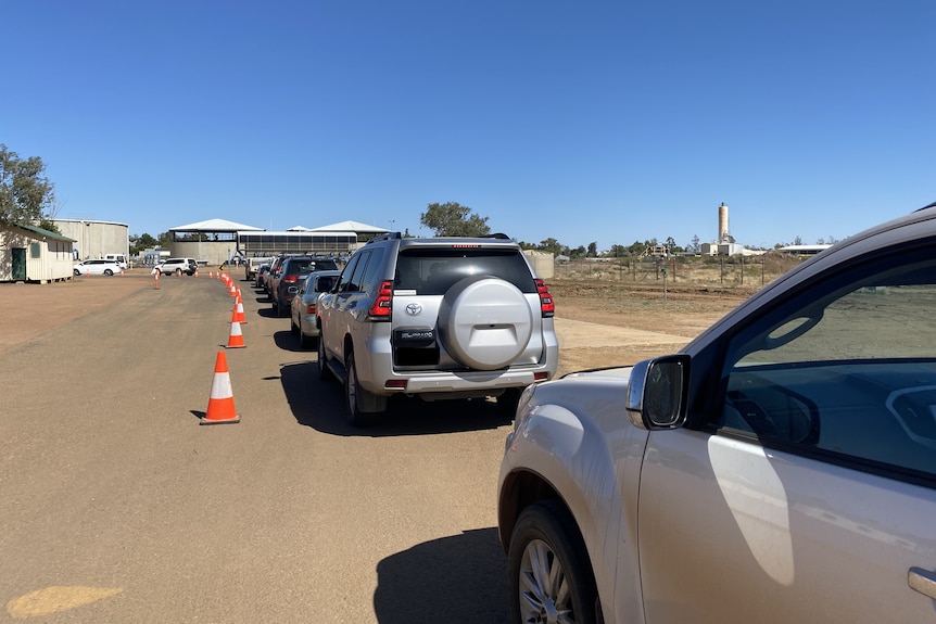 A long line of cars snakes out of view in a car park.