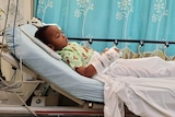 A little African American boy reclining in a hospital bed 