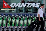 Pilot walks past Qantas sign at Sydney airport