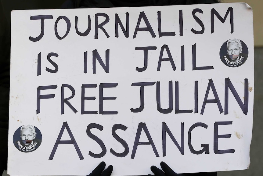 Woman holds banner that reads, "Journalism is in jail. Free Julian Assange".