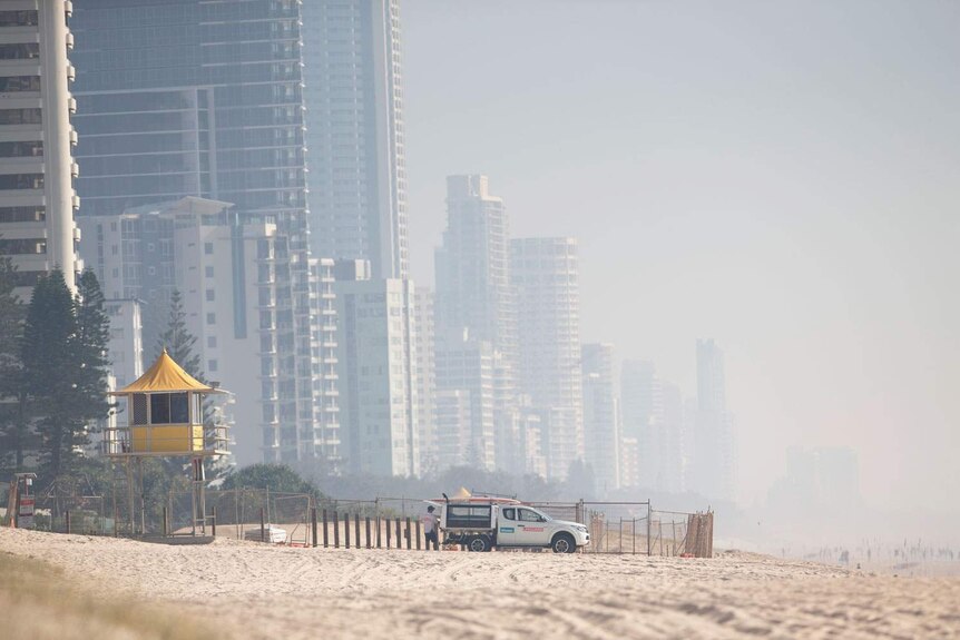 Smoke haze from local bushfires obscures the skyline on the beach at Surfers Paradise
