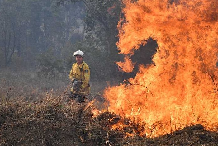 A firefighter standing in front of burning bushland