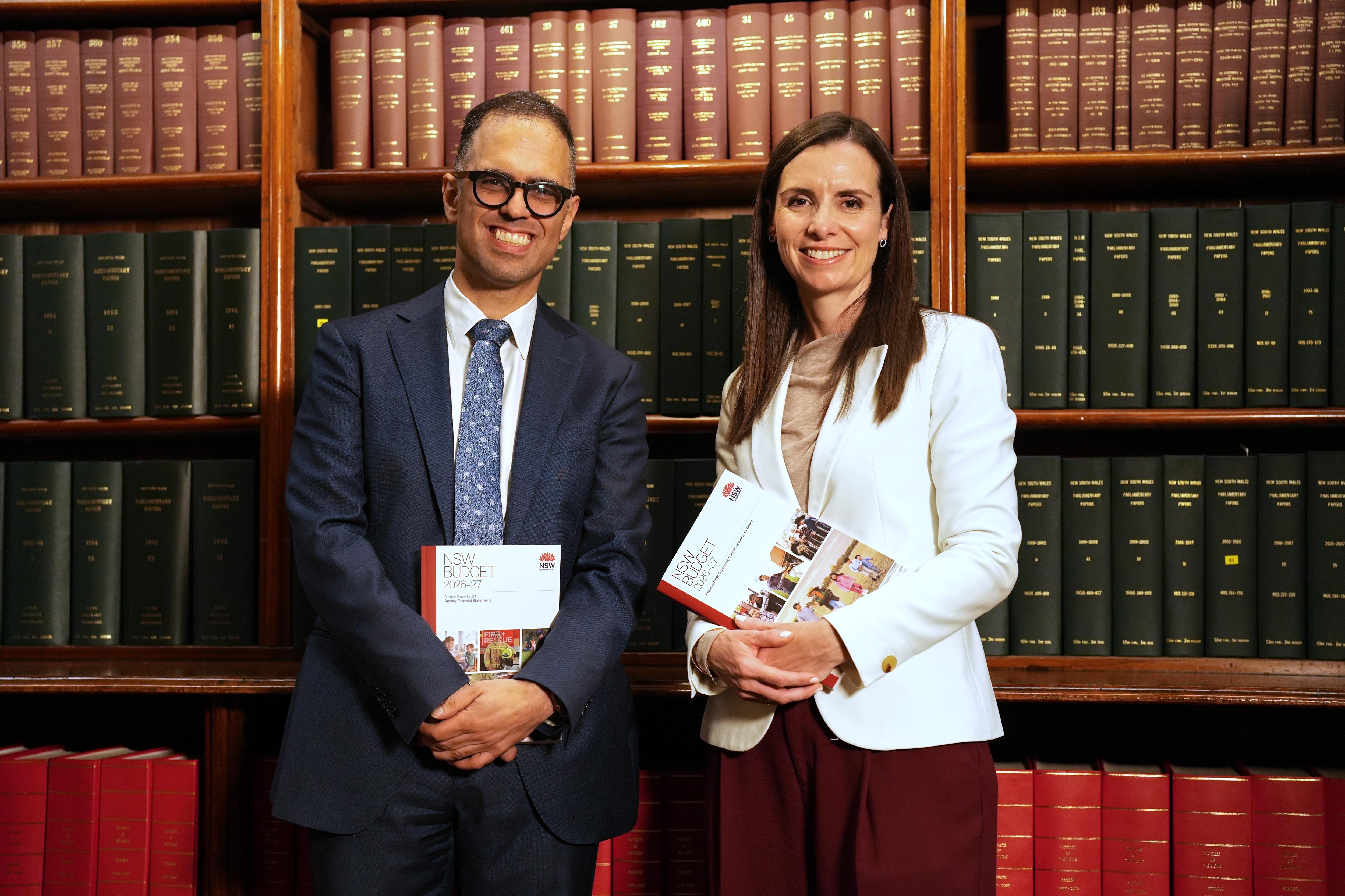 nsw treasurer daniel mookhey holds a copy of the state budget as he stands next to finance minister courtney houssos