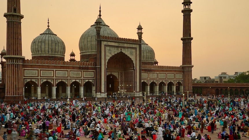 Hundreds of Muslims gather at dusk in the courtyard in front of Delhi's Jama Masjid mosque with picnic blankets and food.