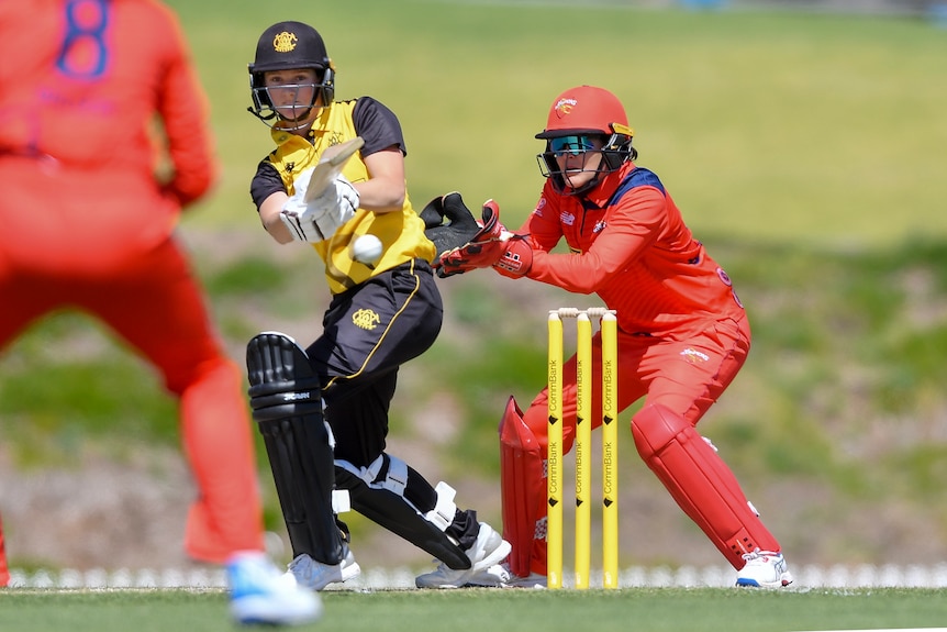 A Western Australia women's cricketer plays a shot on the leg side as the wicketkeeper is poised behind the stumps. 