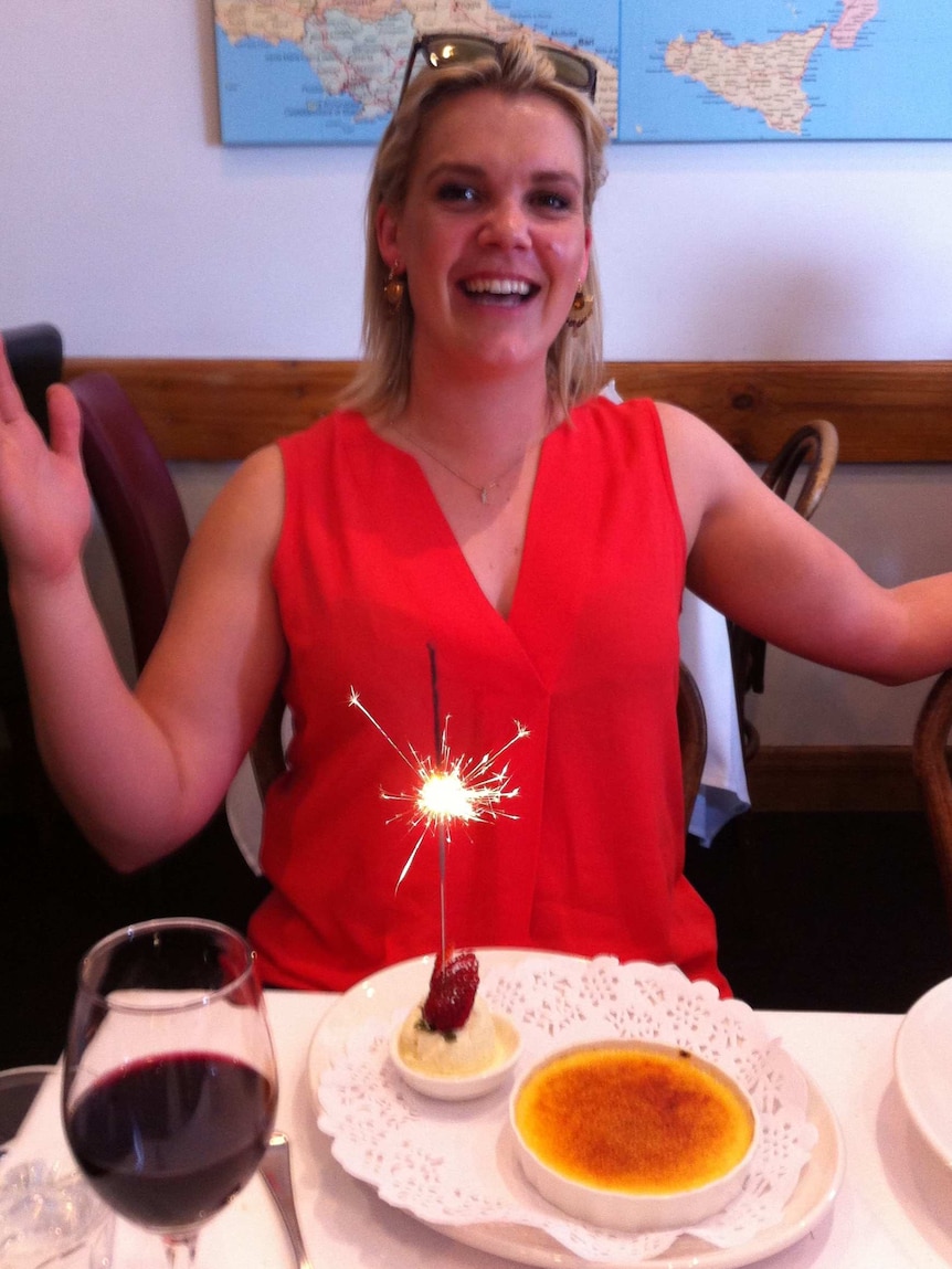 Melissa Sheldon sits at a table with a desert with a sparkler in it
