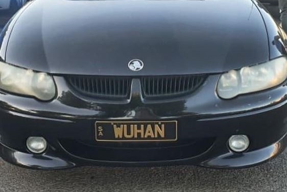 A black car with a gold and black number plate