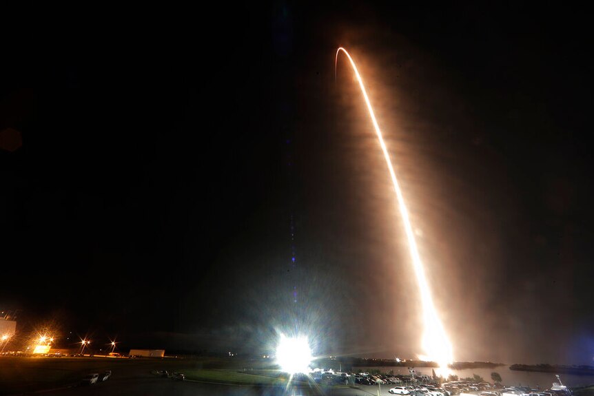 An arc of light from a rocket launch in the night sky