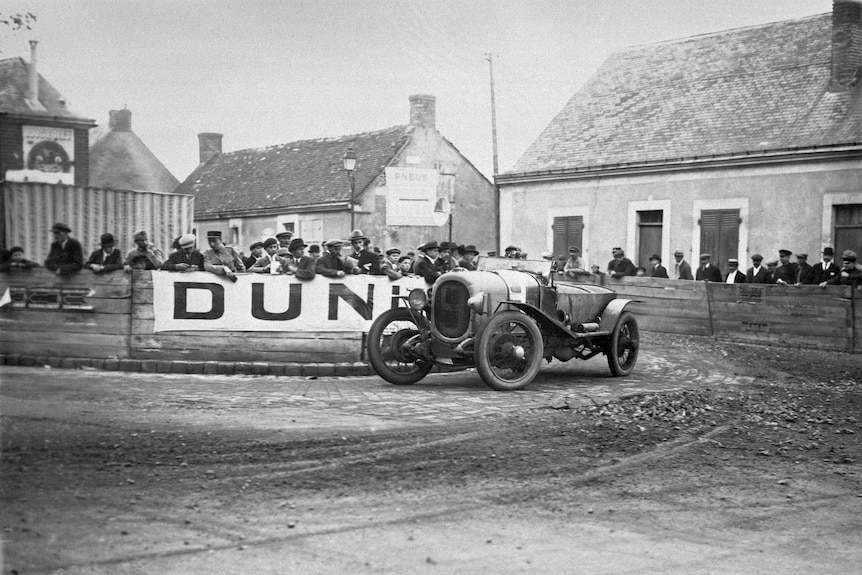 In this black and white photo from 1923, a race car goes around a corner during the first Le Mans 24 Hours.